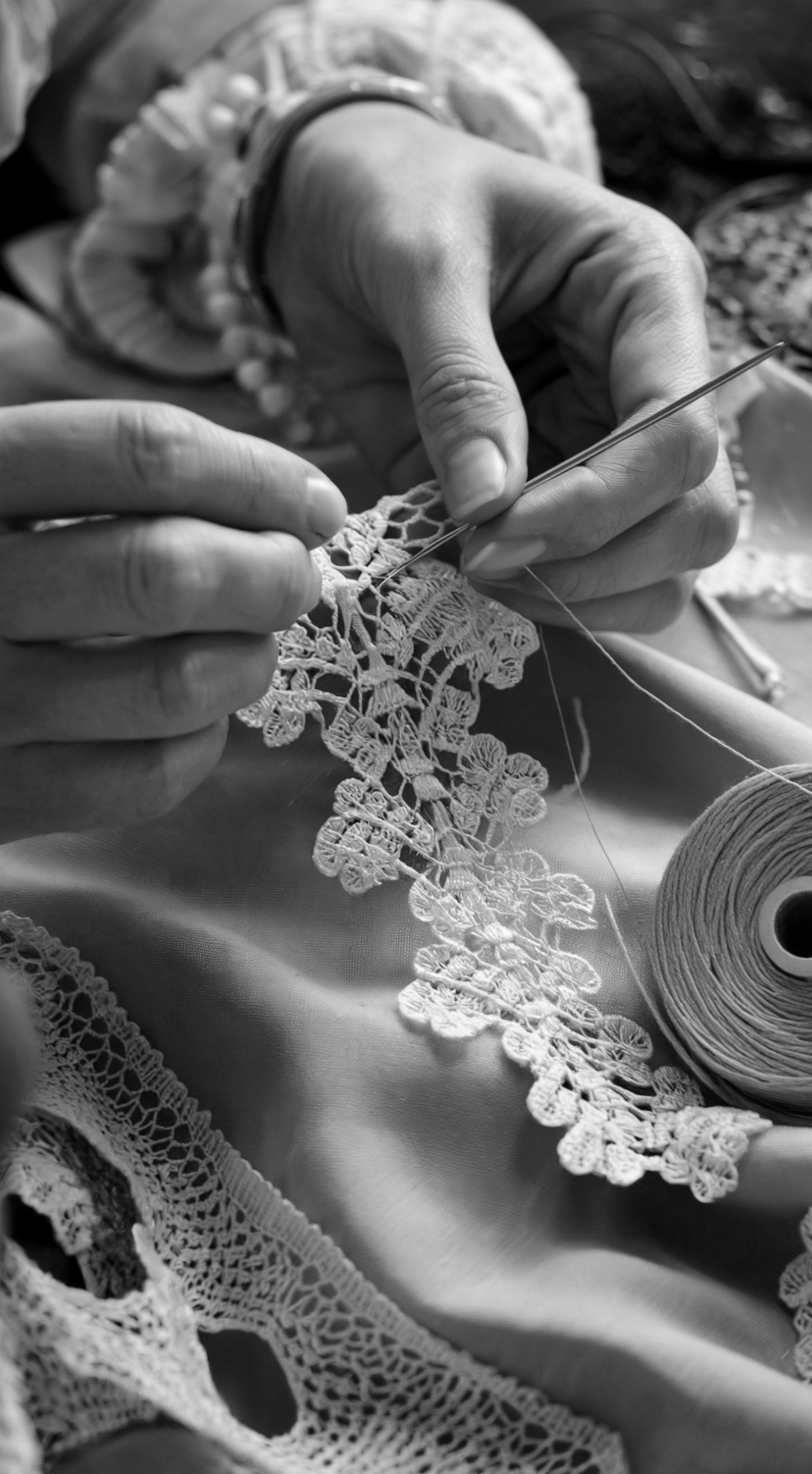 Mani che lavorano un merletto con ago e filo, in bianco e nero